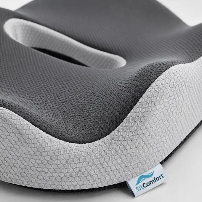 Gray and white ergonomic seat cushion with 'SitComfort' label on a light gray background